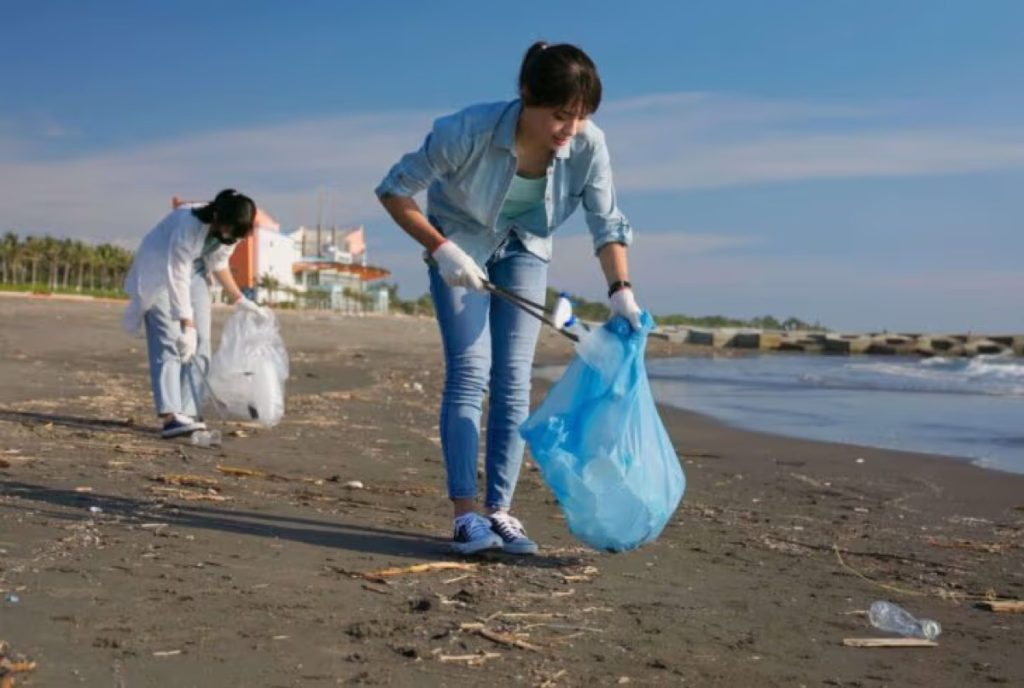 Two volunteers picking up trash on a beach