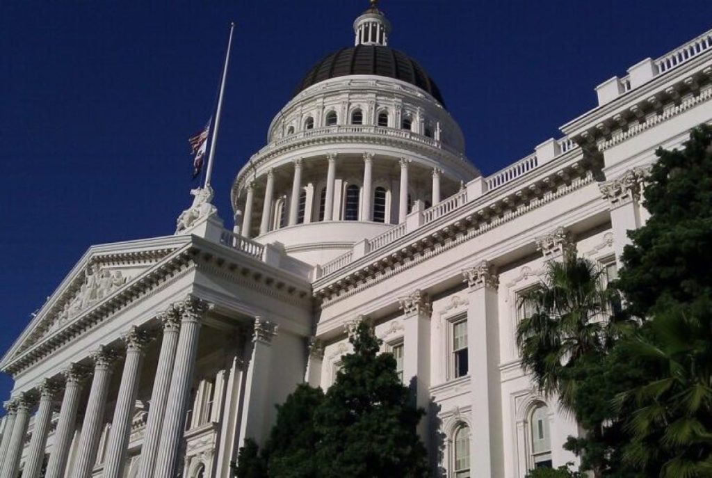 Domed state capitol building lit against a dark blue sky