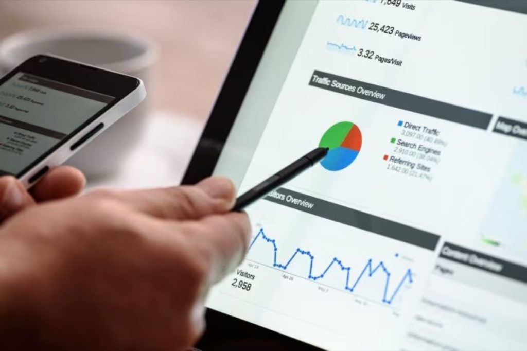 Hand pointing a stylus at an analytics dashboard with charts on a tablet