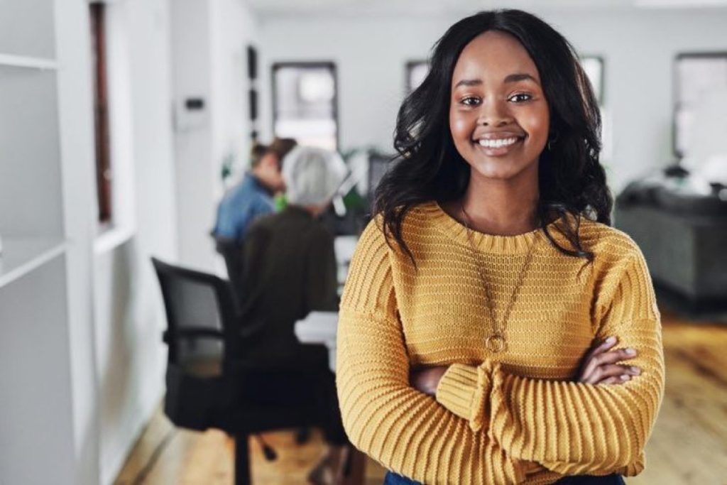Smiling woman with crossed arms standing in a modern office