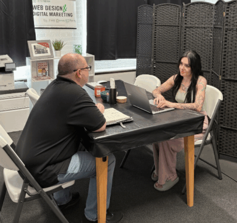 A man and woman sitting at a table with a laptop